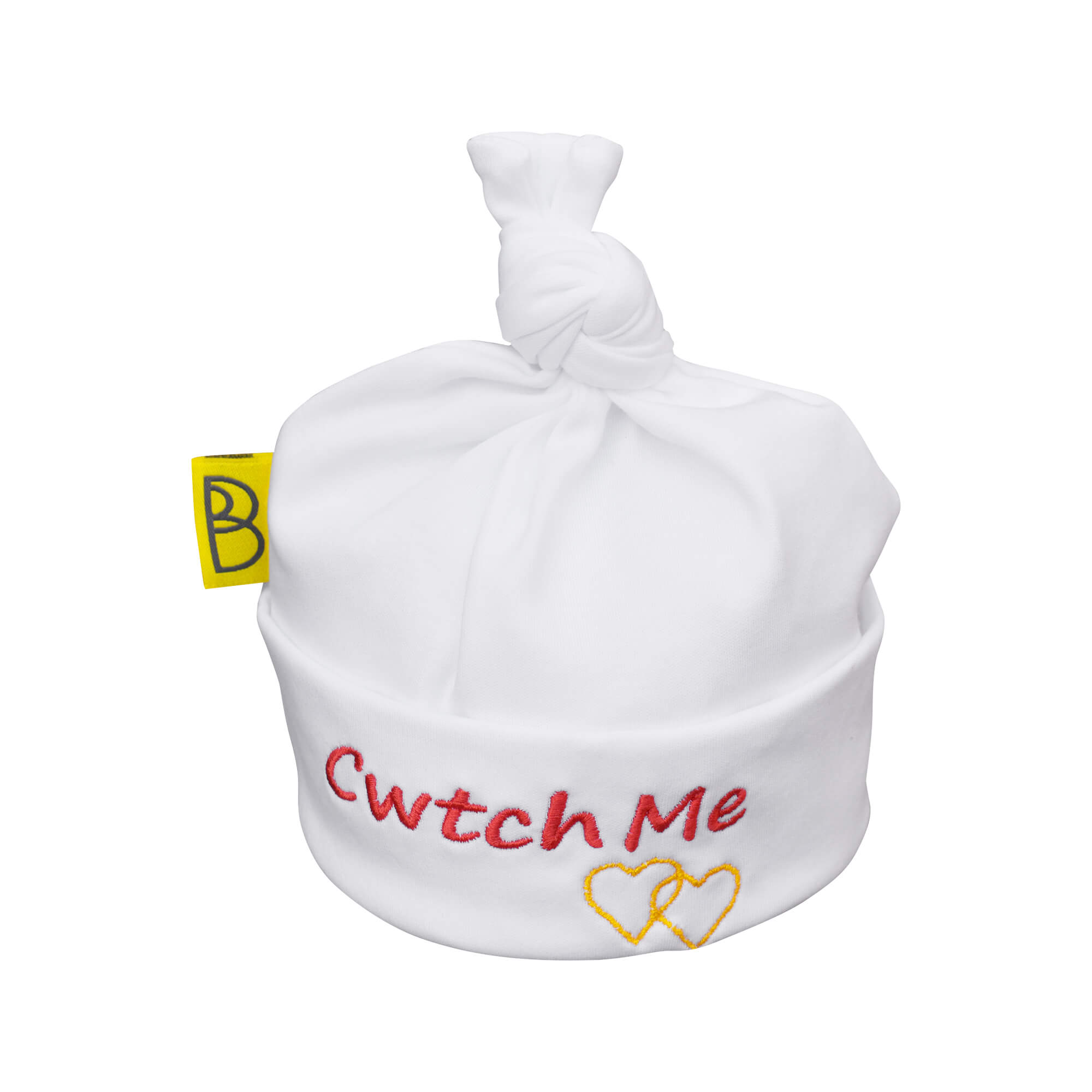 Handmade white Welsh organic cotton baby hat embroidered with words Cwtch Me in red and two yellow embroidered hearts