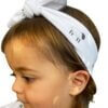 Organic cotton headband around the top of her head, with a bow in our black and white leaping lambs print. Made from GOTs certified organic cotton.