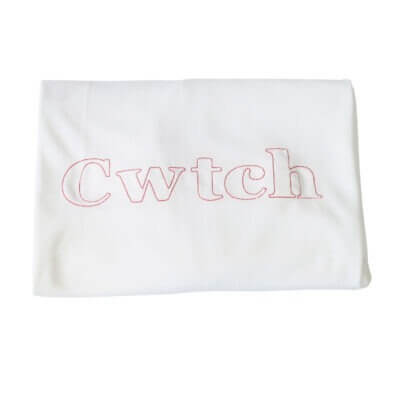 Handmade white Welsh organic cotton baby blanket embroidered with three red dragons and made in Wales