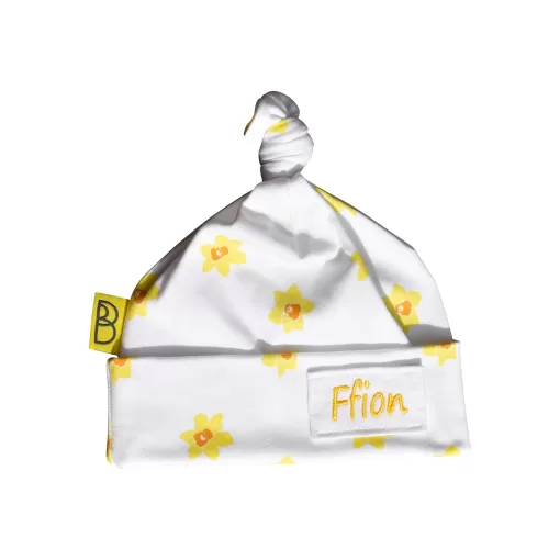 Handmade white organic cotton baby hat with a yellow daffodil design and a knot at the top, can be personalised with name