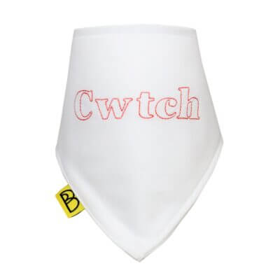 Handmade white Welsh organic cotton baby bib embroidered with word Cwtch in red and have two fastenings to adjust fit