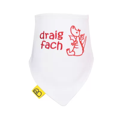 Handmade white Welsh organic cotton baby bib embroidered with a red dragon and words Draig Fach in red