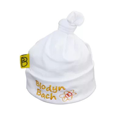 Handmade white Welsh organic cotton baby hat embroidered with a yellow and orange flower and words Blodyn Bach in yellow