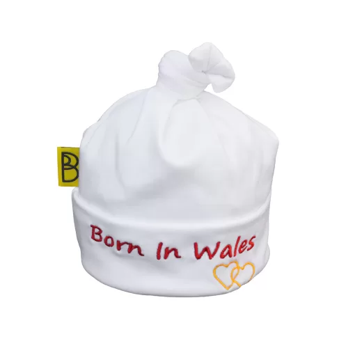 Handmade white Welsh organic cotton baby hat embroidered with words Born in Wales in red and two yellow embroidered hearts