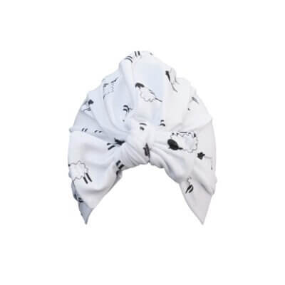 Handmade white organic cotton turban for baby or toddler with a bow in our black and white cute sheep pattern