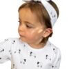 Organic cotton headband around the top of her head, with a bow in our black and white leaping lambs print. Made from GOTs certified organic cotton.