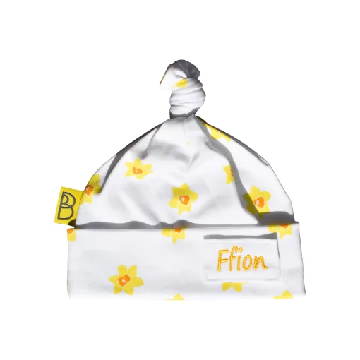 Handmade white organic cotton baby hat with a yellow daffodil design and a knot at the top, can be personalised with name