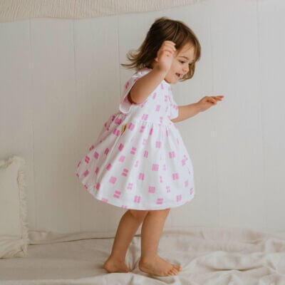 Handmade short sleeve white organic cotton little girl dress with our pink tapestry print with two fasteners to adjust back