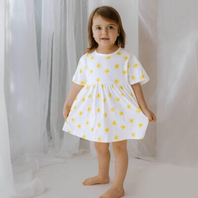 Handmade short sleeve white organic cotton little girl dress with our vibrant daffodil print with two fasteners to adjust back