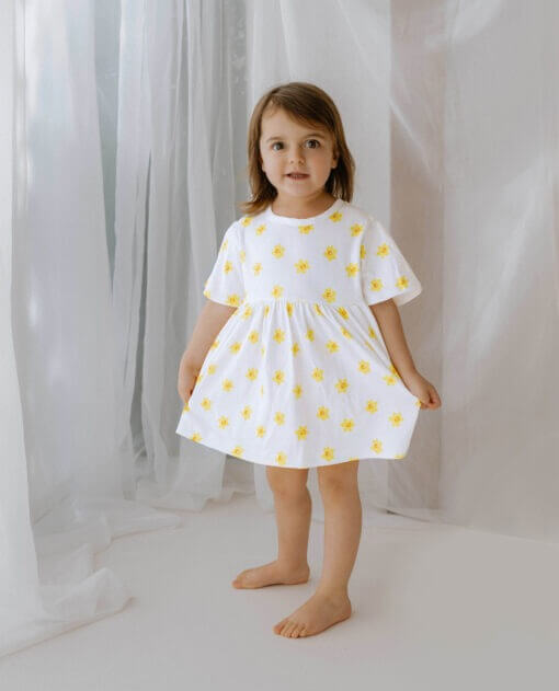 Handmade short sleeve white organic cotton little girl dress with our vibrant daffodil print with two fasteners to adjust back